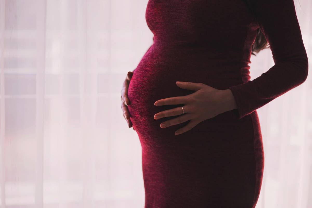 Schwangere Frau haltet ihren Babybauch